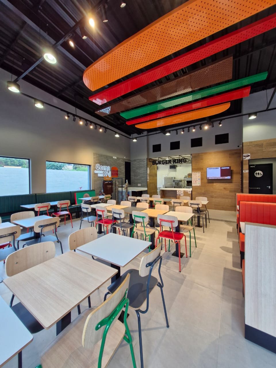 Salão da unidade Burger King, com mesas, revestimentos e iluminação